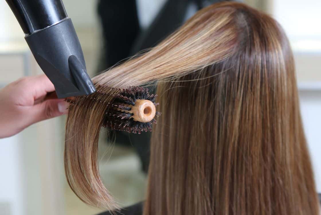Estilista profesional secando el pelo a mujer
