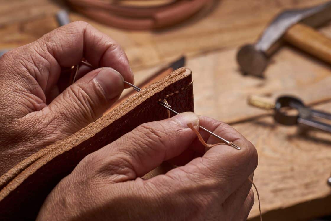 Manos de hombre trabajando el cuero con una aguja